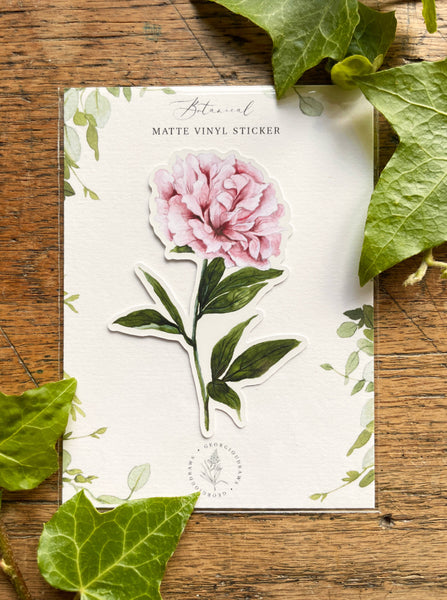 Floral sticker on a card with green leaves on a wooden surface