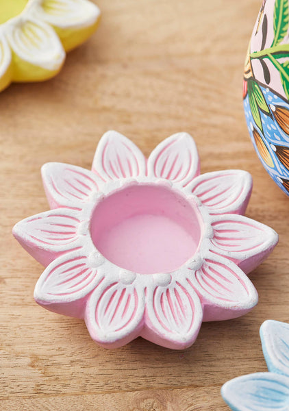 Pink flower-shaped candle holder on a wooden surface