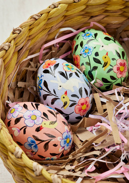 Decorative Easter eggs with floral and bird patterns in a woven basket.