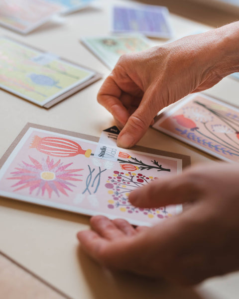 Hands arranging colourful greeting cards on a wooden surface