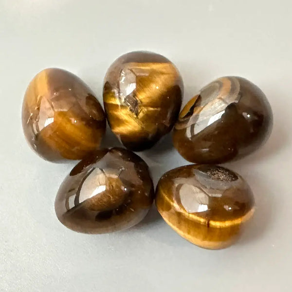 Five brown tiger's eye stones on a white background