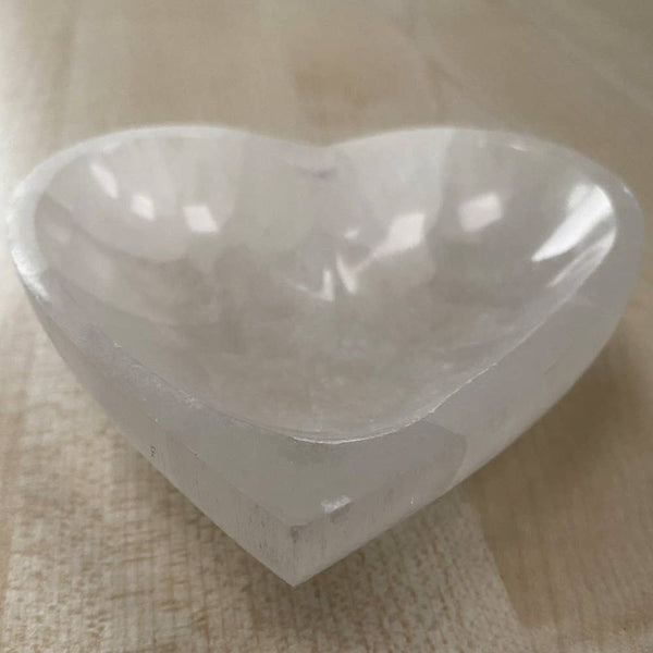 Heart-shaped white bowl on a wooden surface