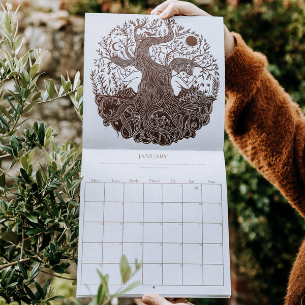 Calendar with nature-themed design held by a person outdoors