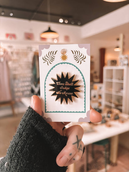 Hand holding a card with decorative pin badge design with text in an indoor setting