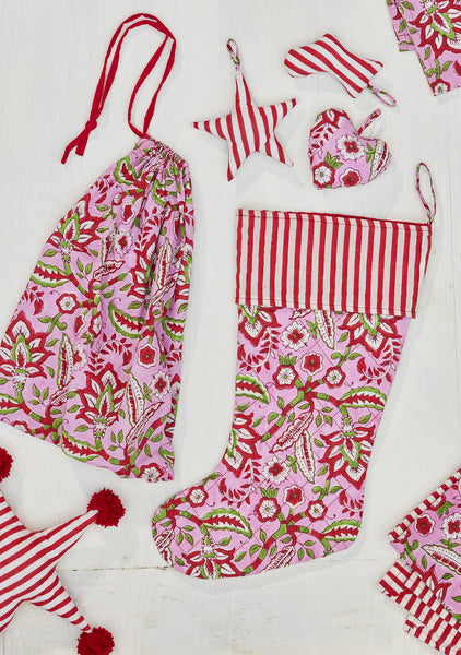 Pink and red patterned children's stocking and decorations on a white background