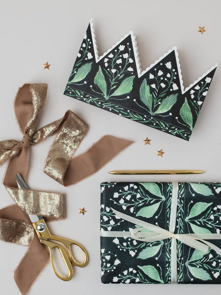 Floral-patterned paper crown, gift wrap with ribbons and scissors on a light background