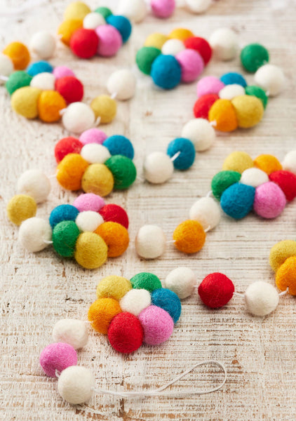 Colourful felt ball garland on a wooden surface