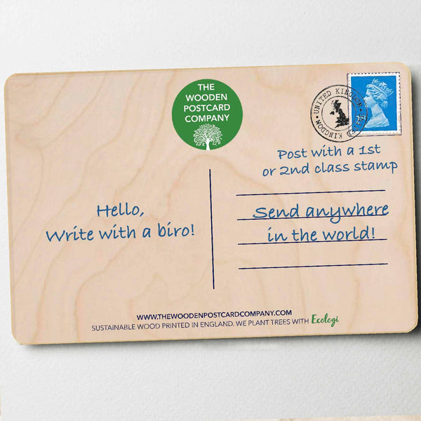 Wooden postcard with text and a stamp on a light gray background