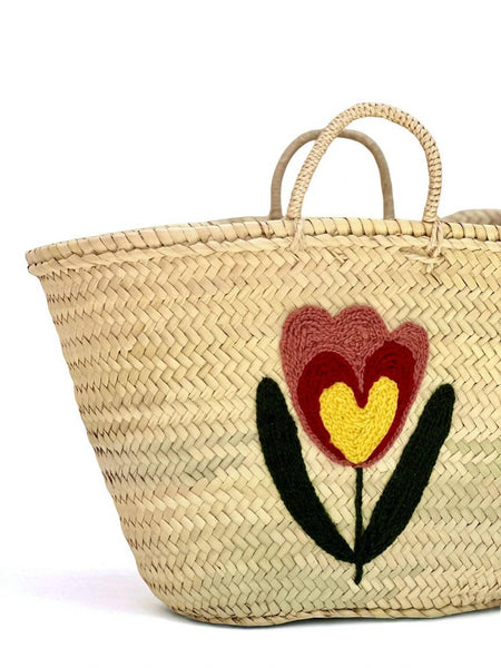 Woven basket with embroidered flower design on a white background