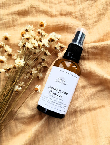 Bottle of 'Among the Flowers' spray on a textured fabric background