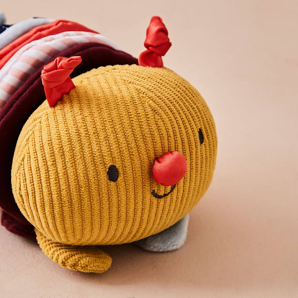 Yellow knitted toy with red accents on a beige background