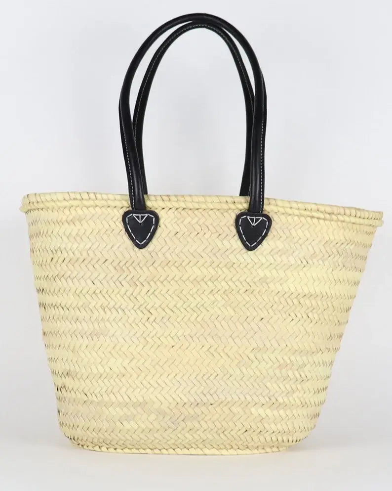 Woven straw tote bag with black handles on a white background