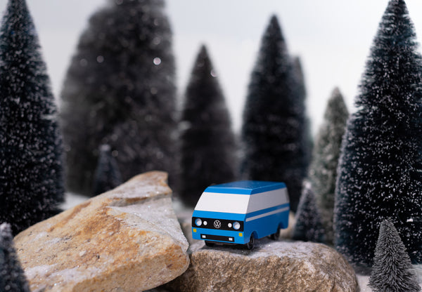 Model Volkswagen van on a rock with Christmas trees in the background
