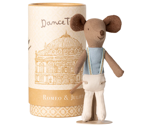 Stuffed toy mouse in a costume standing next to a cylindrical packaging with architectural design and text.