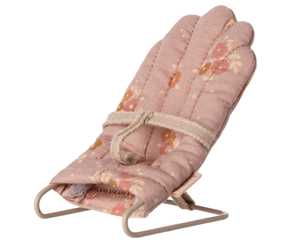 Pink floral babysitter for seating a toy baby rabbit on a white background