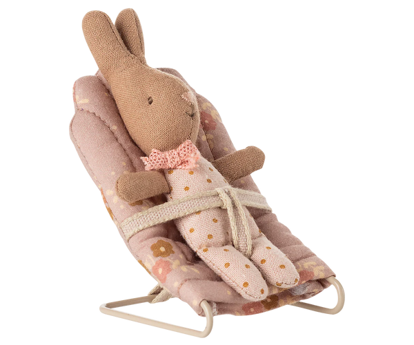 Toy baby rabbit sitting in a pink floral babysitter on a white background