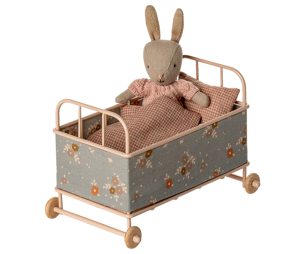 Toy rabbit in a small bed with floral pattern on a white background