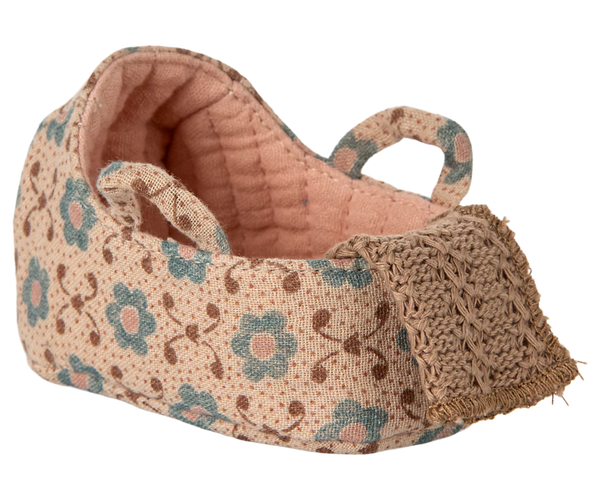 Floral-patterned baby cot with textured fabric on a white background