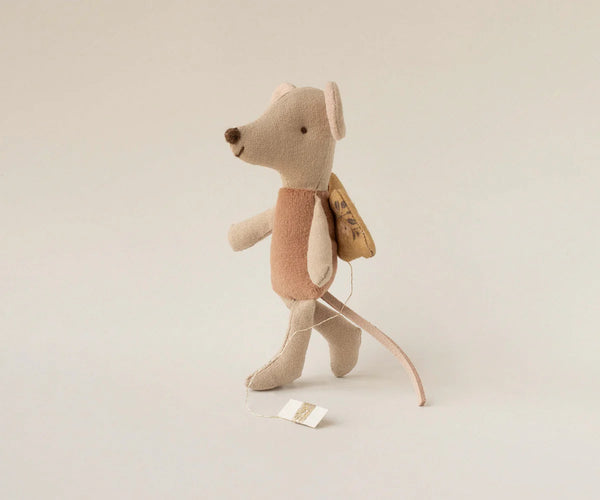 Stuffed mouse toy with a backpack on a beige background