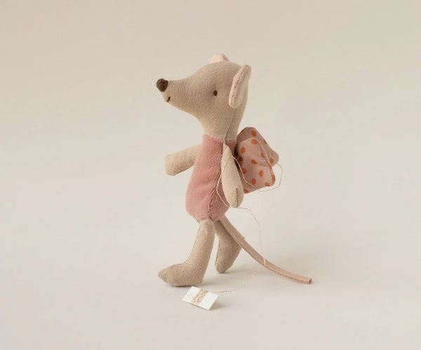 Stuffed mouse toy with a pink dress and fairy wings on a beige background