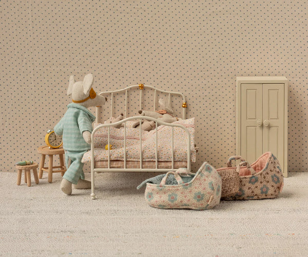 Miniature bedroom scene with a child's bed, toys, and furniture against a patterned wall.