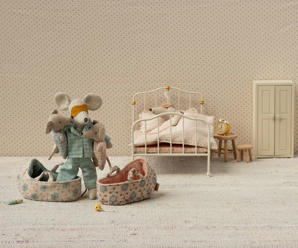 Miniature bedroom scene with toy mice and furniture against a patterned wall.