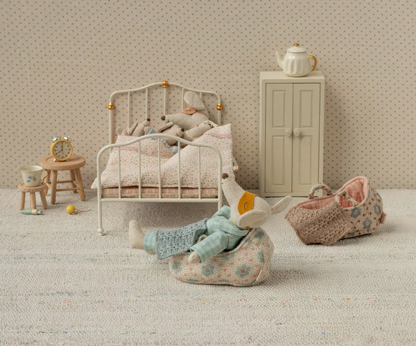 Miniature bedroom scene with a bed, dresser, and toys on a textured surface.