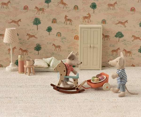 Miniature toys in a room with wallpaper featuring animals and trees.