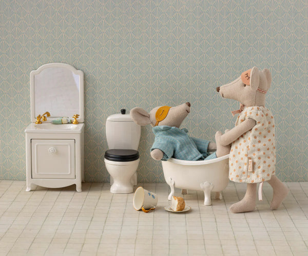 Stuffed animal toys in a bathroom setting with a sink, toilet, and bathtub.