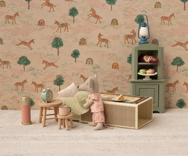 Miniature dollhouse scene with a toy mouse, furniture, and decorative items against a wallpaper with horse pattern.