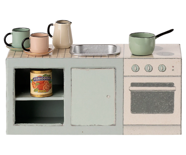 Miniature kitchen set with oven, sink, and mugs on a white background
