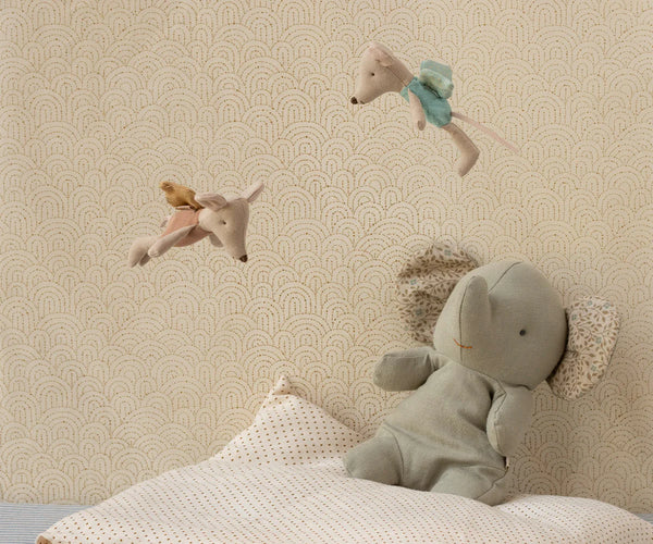 Children's room with stuffed animals on a bed against a patterned wall.