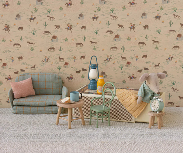 Children's room with toy furniture and decor against a patterned wallpaper.