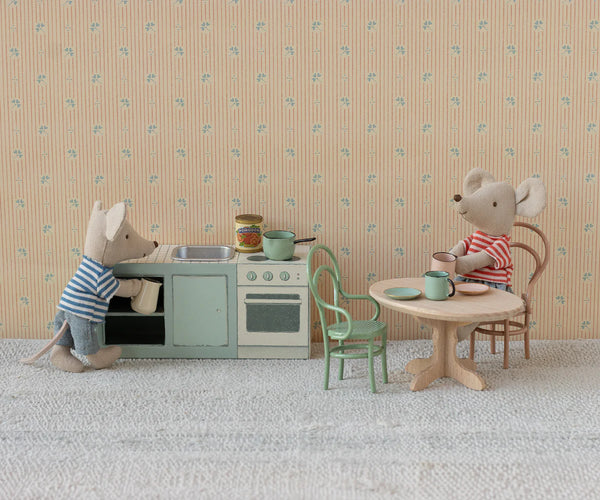Two toy mice in a kitchen setting with a sink, stove, and table.