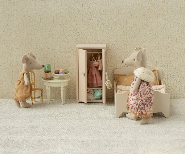 Miniature room setup with toy mice and furniture against a patterned wall.