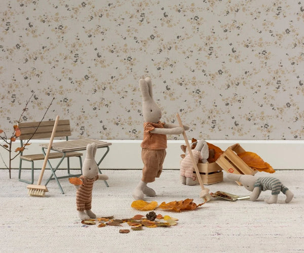 Miniature rabbit figures with autumn accessories on a floral wallpaper background