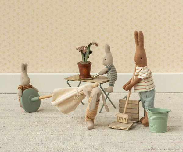 Miniature scene with toy bunnies engaged in cleaning activities on a wooden floor.