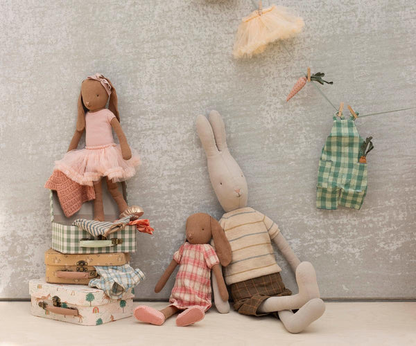 Three stuffed rabbit dolls against a textured wall background