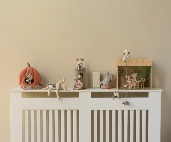 Decorative shelf with small figurines on a white cabinet against a beige wall