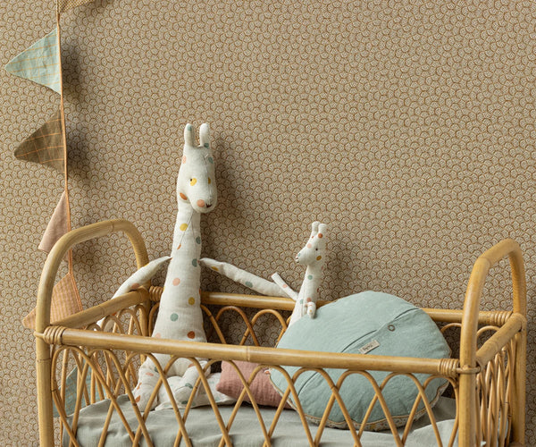 Children's room with a rattan crib, plush toys, and decorative elements against a patterned wall.