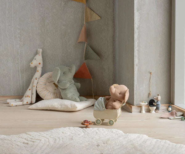 Children's toys and plush items on a wooden floor against a neutral wall.