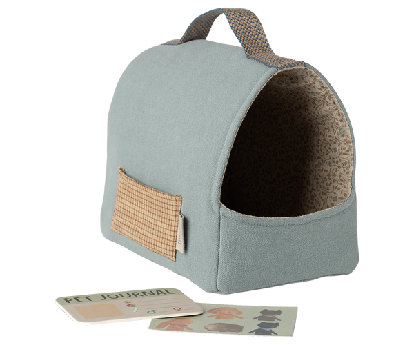 Pet bed with a handle and a small pouch, accompanied by a pet journal and stickers on a white background.