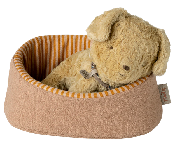 Beige plush dog toy in a striped pet bed on a white background