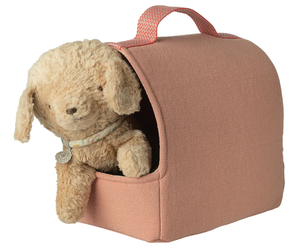 Pink pet carrier with a beige dog inside on a white background