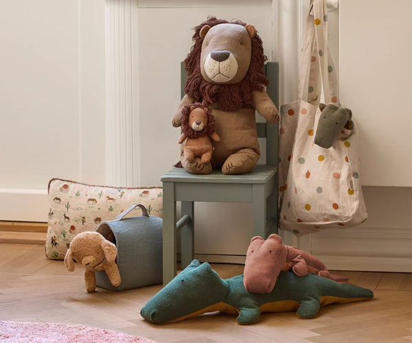 Plush toys including a lion, puppy and crocodile on a chair and floor.