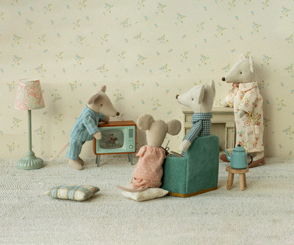 Miniature scene with toy animals in a room setting, including a mouse on a couch and another on a chair.