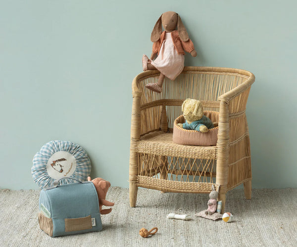 Wicker children's chair with stuffed toys against a light green wall