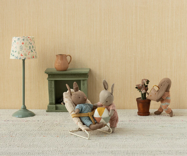 Miniature scene with stuffed animals in a room setting, including a lamp, fireplace, and decorative items.