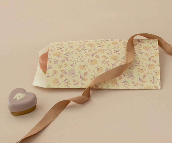 Floral-patterned envelope with a ribbon and heart-shaped box on a beige background