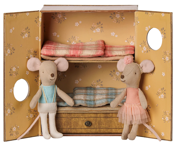 A dollhouse-style bedroom with floral yellow doors and shelves, displayed open with two plush mouse dolls and folded bedding inside.